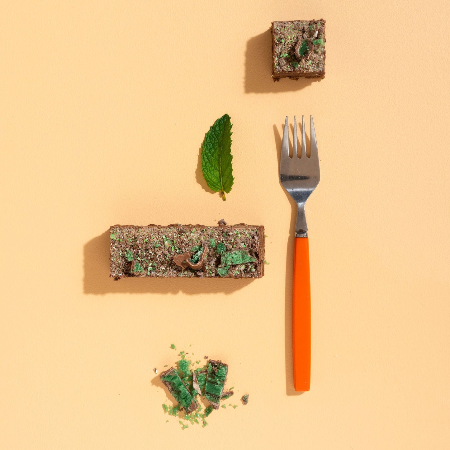 Fork with a piece of cake and a leaf on a beige background