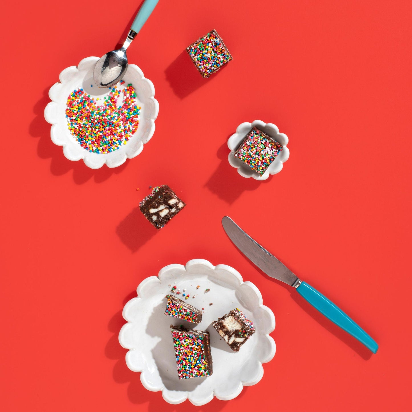 Slices of cake with colorful sprinkles on white plates with a red background