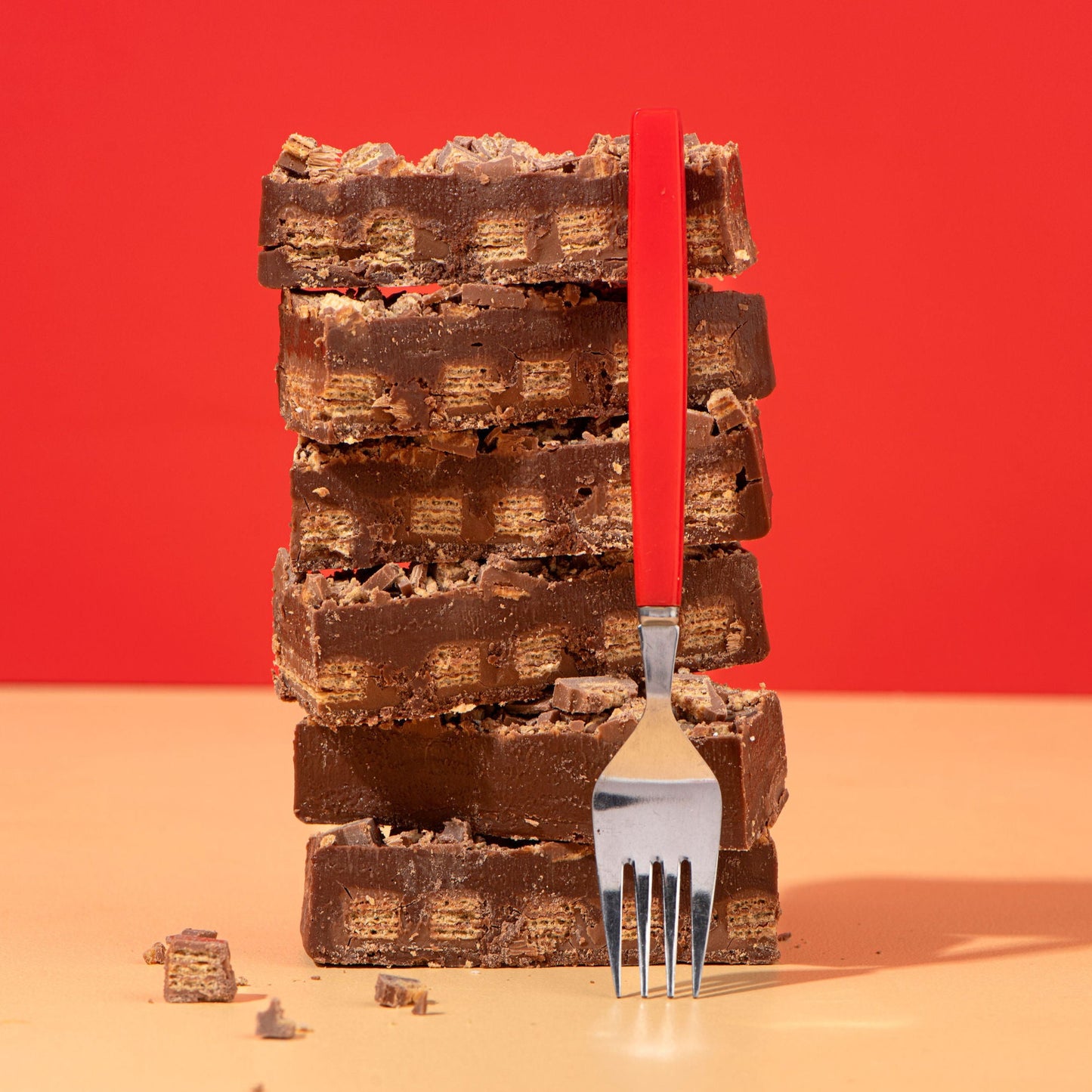 Stack of chocolate bars with a fork against a red background