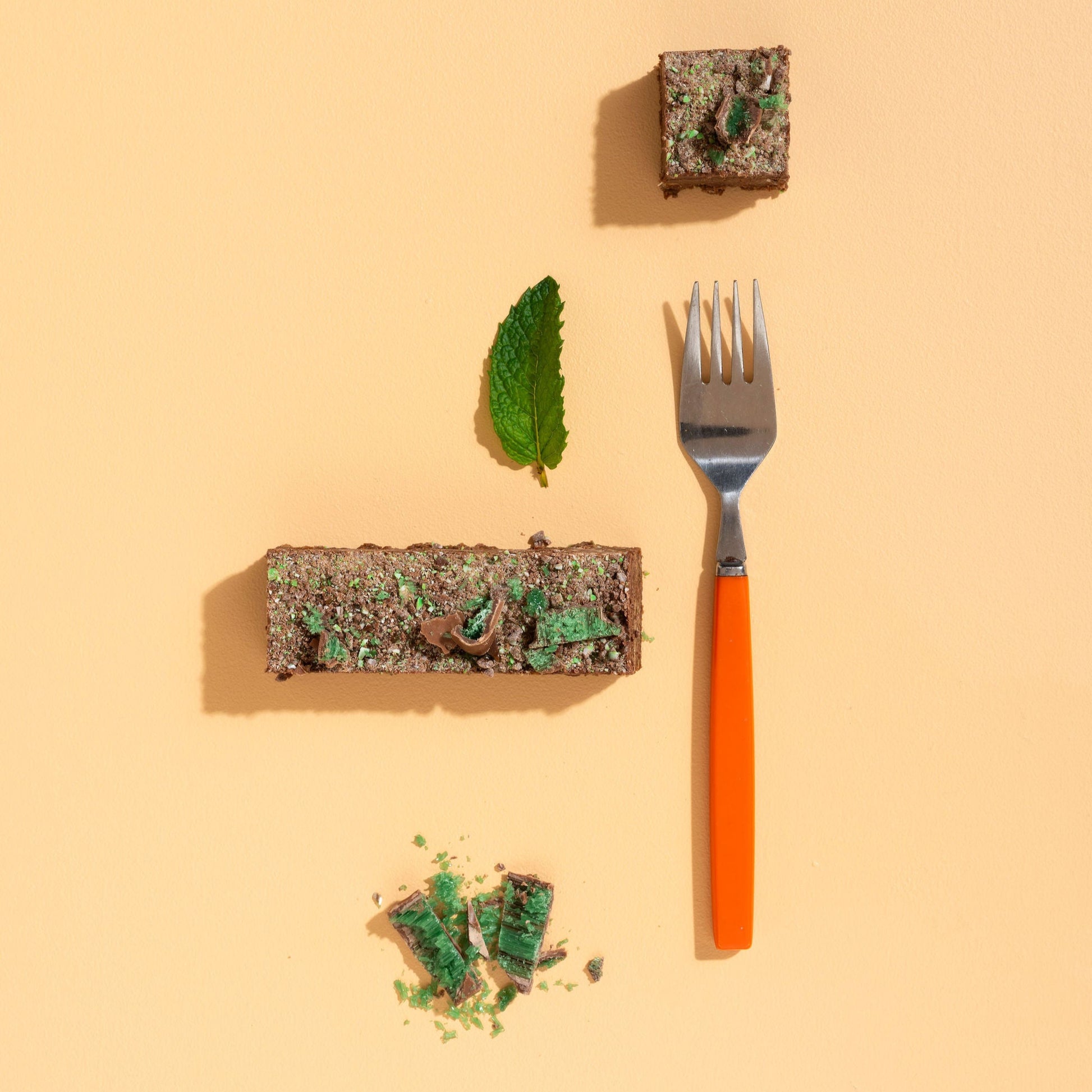 Fork with a piece of cake and a leaf on a beige background