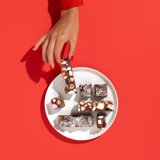Hand holding a plate of brownies against a red background