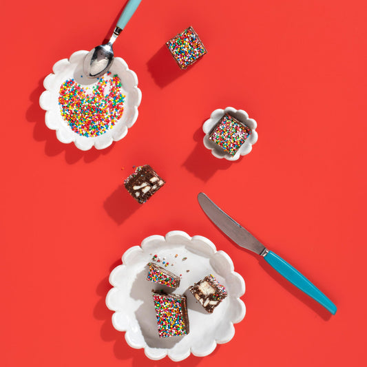 Slices of cake with colorful sprinkles on white plates with a red background