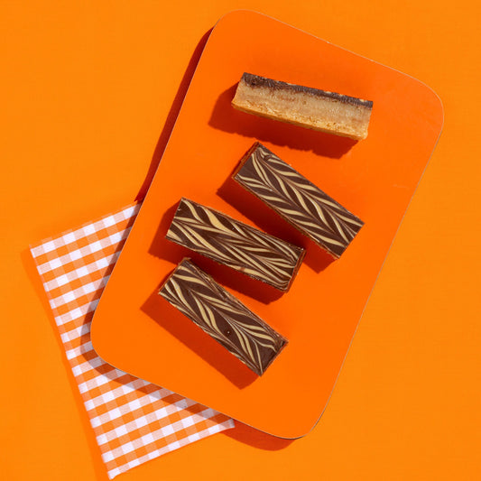 Four chocolate bars with a marbled pattern on an orange tray against an orange background.