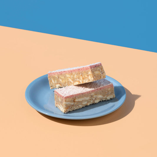 Two layered dessert bars on a blue plate against a blue and beige background