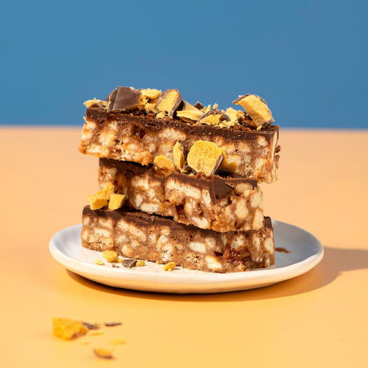 Stack of dessert bars with chocolate and crumbly topping on a blue background