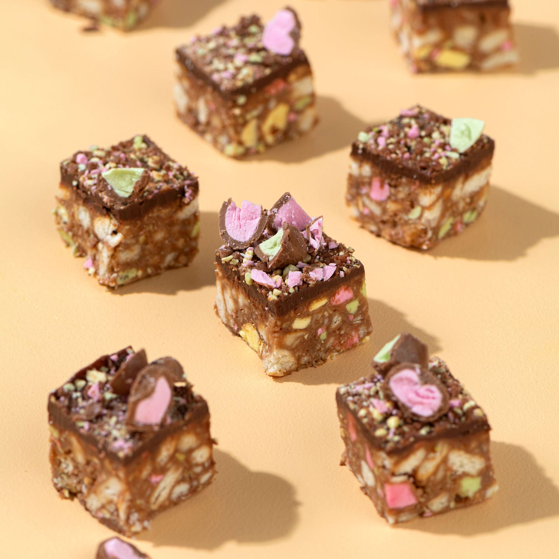 Chocolate-covered treats with colorful toppings on a beige background