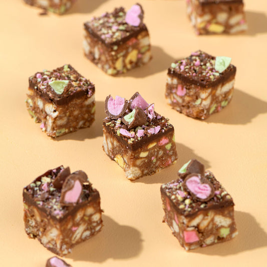 Chocolate-covered treats with colorful toppings on a beige background