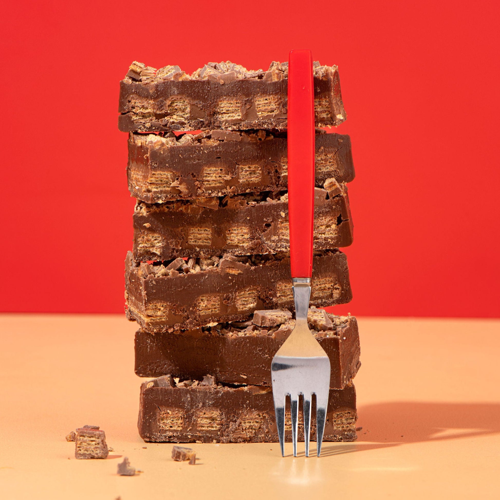 Stack of chocolate bars with a fork against a red background