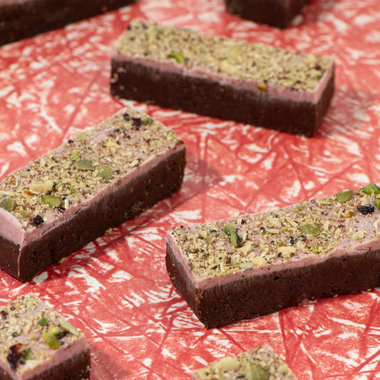 Chocolate bars with green pistachio pieces on a red textured surface